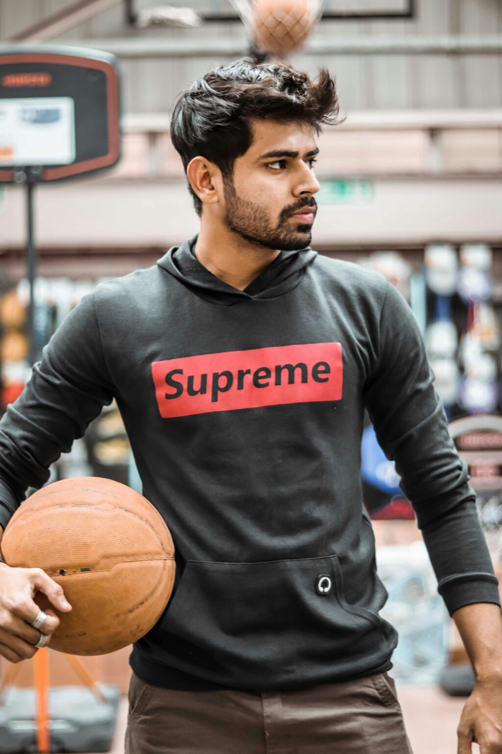 SMM Portrait of a young man holding a basketball on an indoor court in Ahmedabad, India.