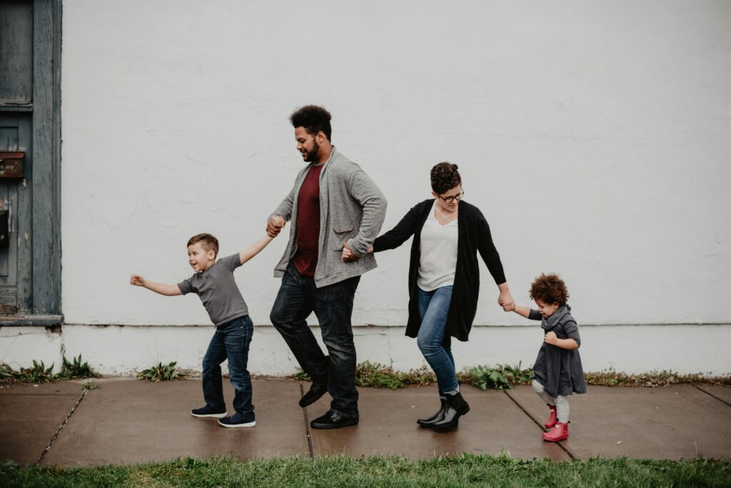 Top 7 Affordable Fashion Trends You Need This Season A joyful family walking together outdoors, holding hands in a playful and happy moment.
