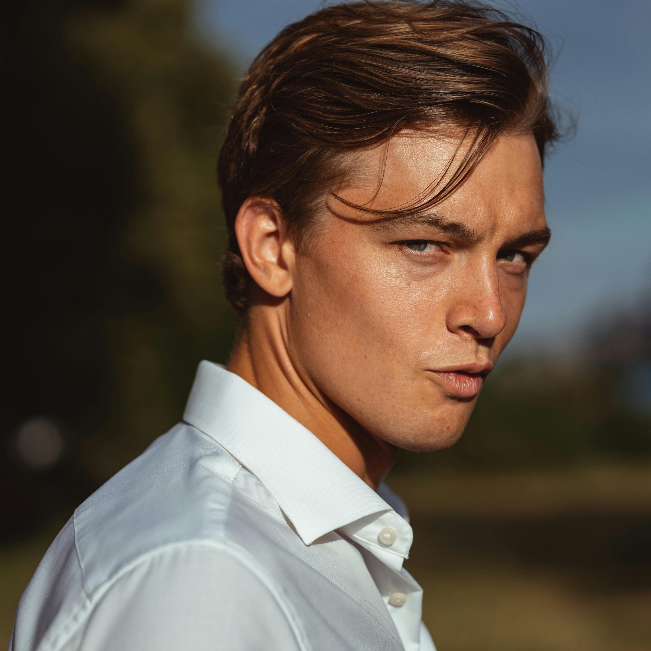 Home Portrait of a young man outdoors with sunlight creating strong shadows on his face.