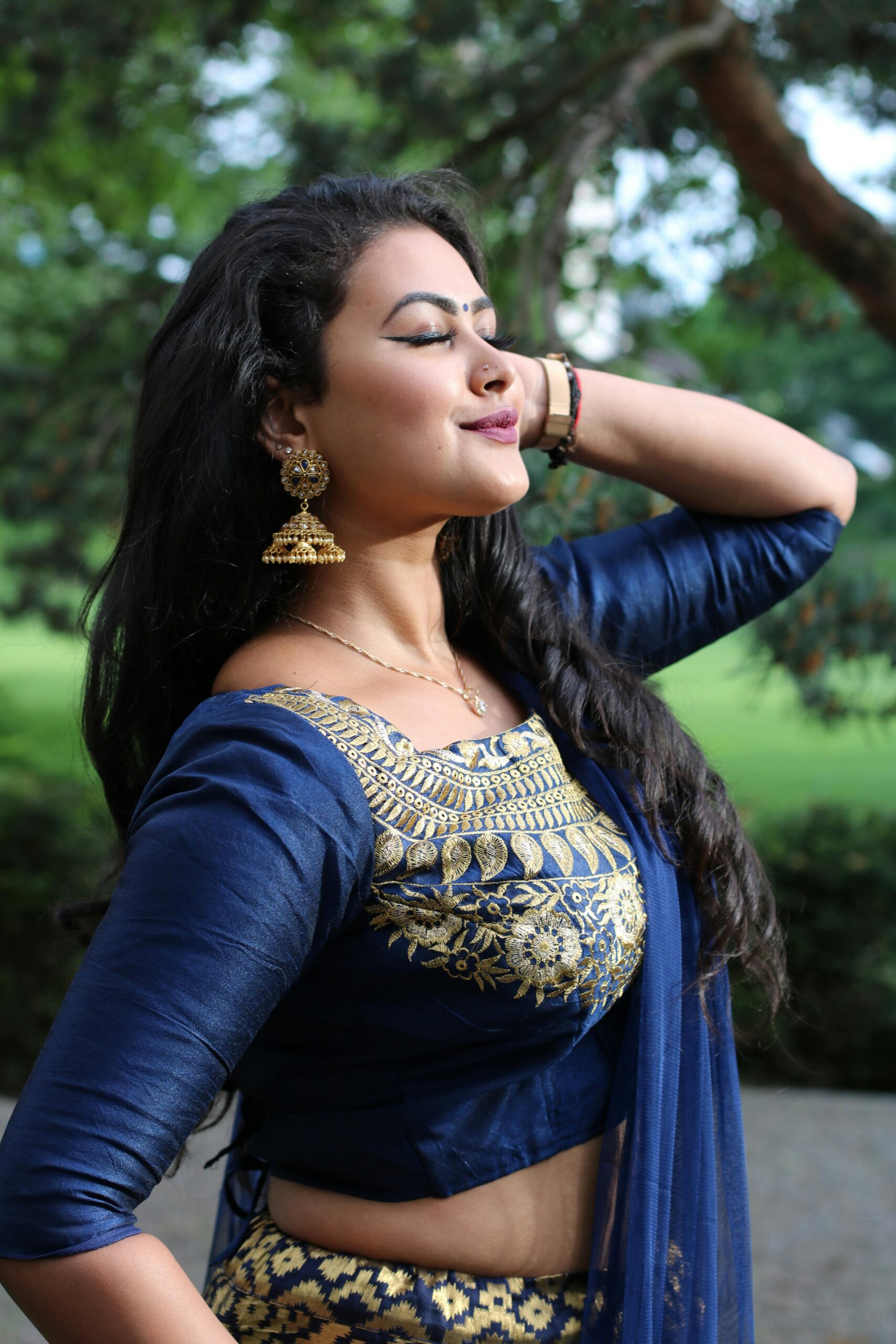 Home Portrait of a woman in traditional blue and gold attire, posing outdoors.