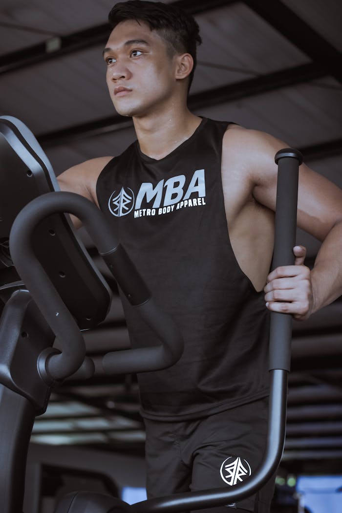 From below of concentrated muscular male wearing t shirt exercising on ellipsoid machine during intense training in modern gym in daytime